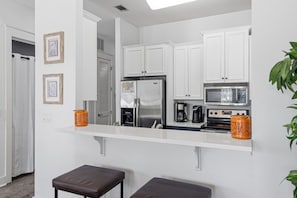 A modern kitchen with white cabinets, stainless steel appliances, and a white countertop.