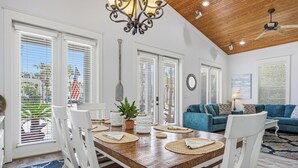 A dining area with a wooden table, white chairs, and a chandelier. - SEA-REST!! Relaxed 4br 4ba home, POOL and close to the BEACH! (Alys Beach)