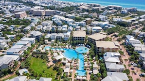 An aerial view of a resort with a central swimming pool, multiple buildings, and a coastline in the background. - SEA-REST!! Relaxed 4br 4ba home, POOL and close to the BEACH! (Alys Beach)
