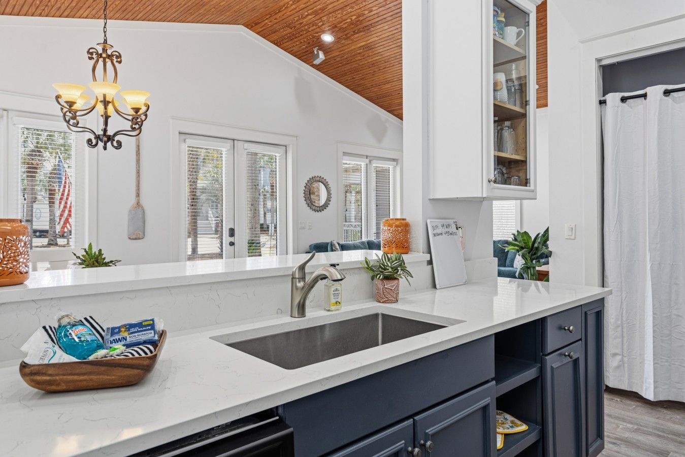 A modern kitchen with a white countertop, dark cabinets, and a wooden ceiling.