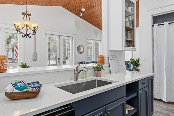 Une cuisine moderne avec un plan de travail blanc, des meubles de couleur sombre et un plafond en bois.