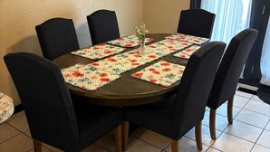 Un coin repas avec une table ronde, des chaises noires et un set de table à motifs floraux.