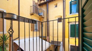A courtyard with a metal railing, a small table, and a staircase leading to a balcony.