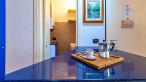 A kitchen area with a blue countertop, a coffee machine, and a tray with two cups.