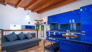 A modern kitchen with blue cabinets and a wooden ceiling.