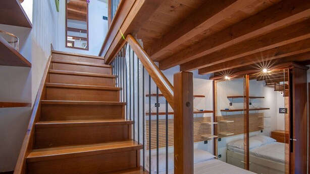 A wooden staircase leading to a bedroom with bunk beds.