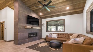 Un salon moderne avec une cheminée, un canapé en cuir et un ventilateur de plafond.