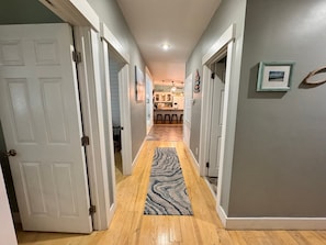 Enter a hallway leading to a kitchen area with doors, a rug, and a bar counter.