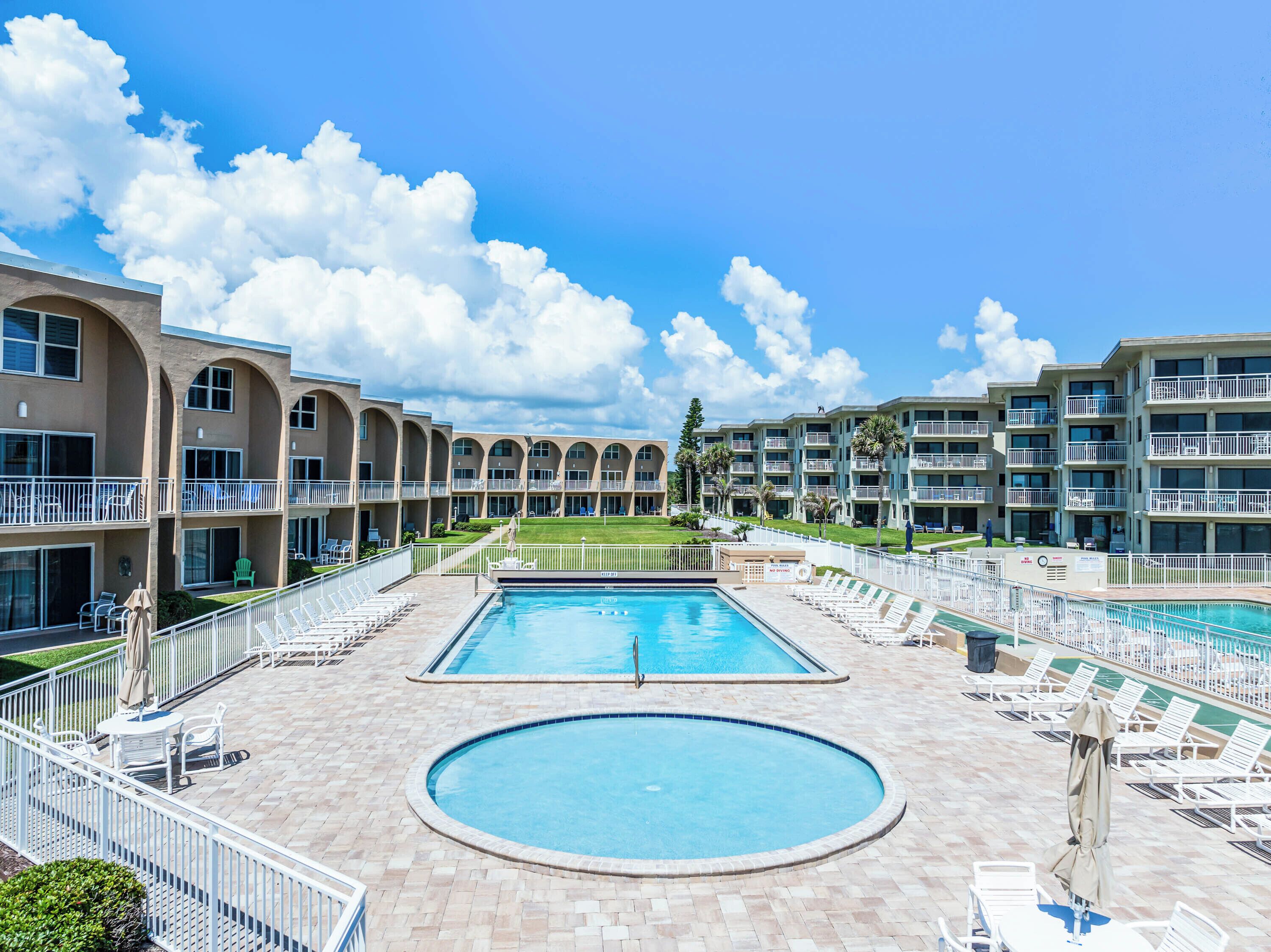 Un hôtel doté d’une piscine, de plusieurs balcons et d’une pelouse bien entretenue.