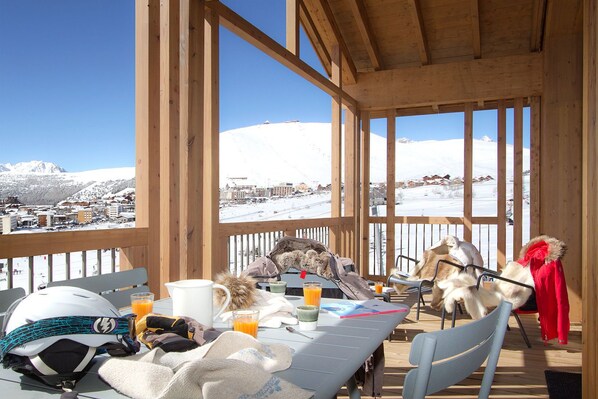 Enjoy a meal with a mountain view from this outdoor dining area, featuring a table set with a mug, glass, and notebook.