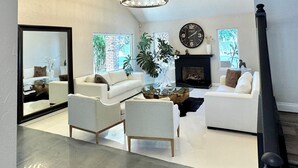 A spacious living room with a modern chandelier, white sofas, a glass coffee table, and a fireplace. - w/pool 5 min to the Strip (Las Vegas)