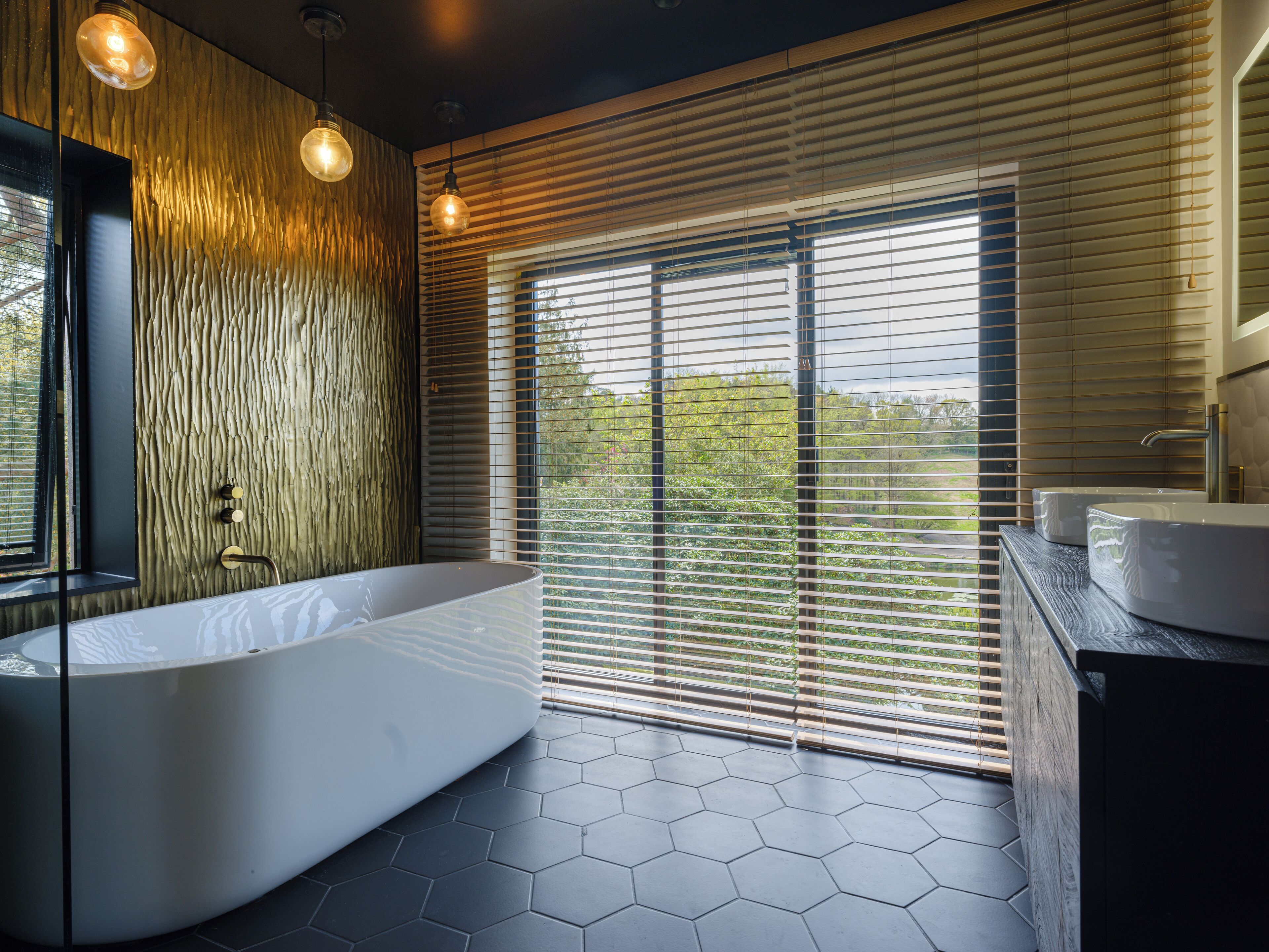 A modern bathroom with a large bathtub, wooden wall panels, and a view through large windows.