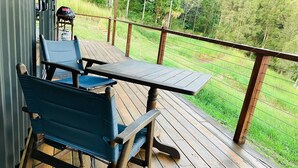 Eine Holzdiele mit Tisch und Stühlen mit Blick auf eine Wiese.