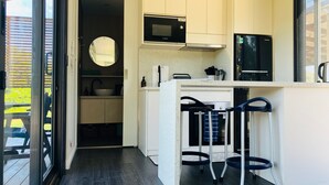 Eine moderne Küche mit weißen Schränken, einer Bosch-Mikrowelle, einem Samsung-Kühlschrank und einer Bar mit Barhocker.
