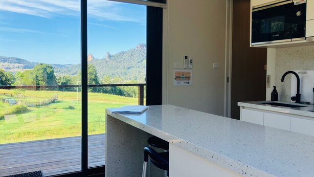 Eine moderne Küche mit einem großen Fenster, einer Bosch-Mikrowelle und Blick auf eine grüne Landschaft.