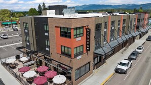 A building with a brick facade, a sign reading "MONACO", and a restaurant named "Monaco Steakhouse & Sports Bar" with outdoor seating. - Beautifully Designed, Fully Stocked New Condo with Custom Features - Plus A Gym! (Columbia Falls)