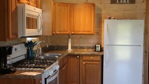 A kitchen with wooden cabinets, a white refrigerator, a stove, and a sink.