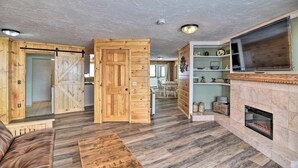 A spacious living area with a fireplace, wooden flooring, and a dining area with a table and chairs. - Kineo Overlook (Beautiful Mountain Views) (Rockwood)