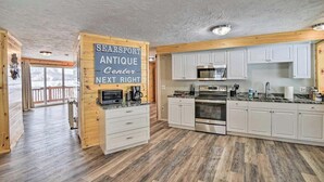 A spacious kitchen with white cabinets, a stainless steel oven, and a microwave. A sign indicates an antique center next right. - Kineo Overlook (Beautiful Mountain Views) (Rockwood)