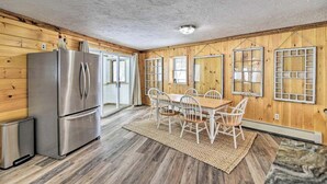 A compact kitchen with a stainless steel refrigerator, a dining table with chairs, and wooden walls. - Kineo Overlook (Beautiful Mountain Views) (Rockwood)