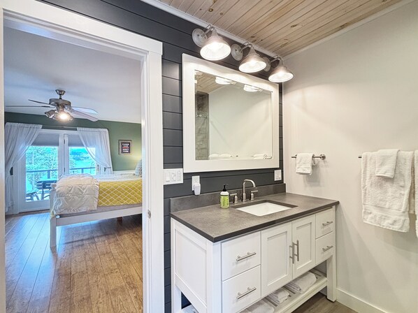 A bathroom with a large mirror, white cabinets, and a sink. - Sunset Lodge (Waterfront on Moosehead Lake with Breathtaking Views!) (Greenville)