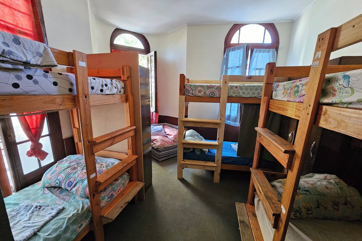 Quarto com beliches, janela com cortinas e porta.