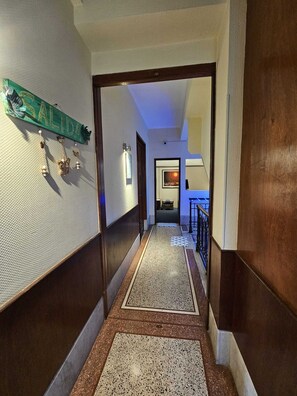 A hallway with a textured wall, a green sign, and a door leading to a room. - Montevideo Hostel (Montevideo)