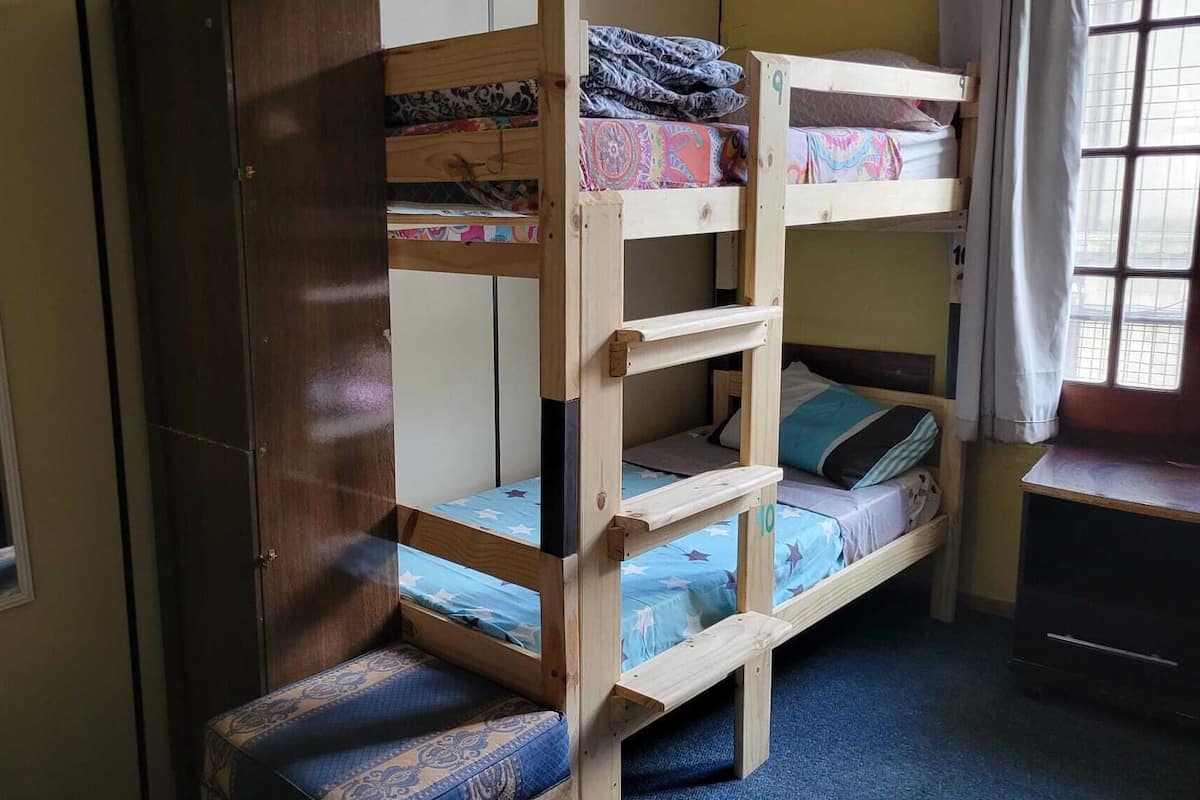 Quarto com beliche, espelho, escrivaninha e janela.
