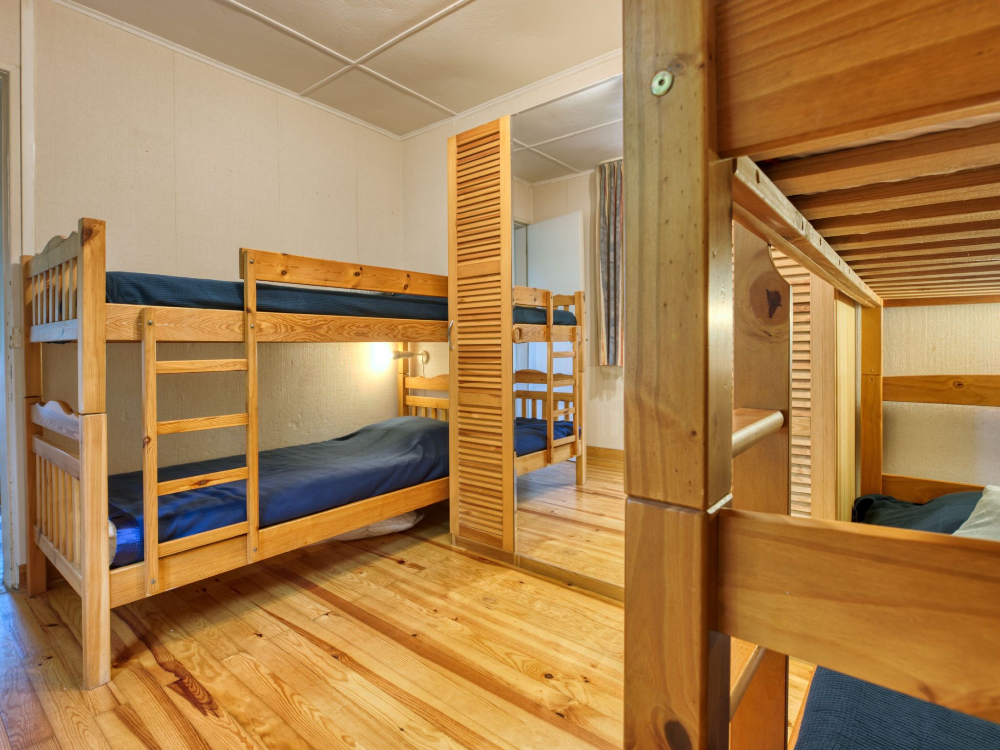 Una habitació de dormitori amb lliteres, terres de fusta i una finestra.