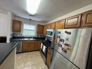 A kitchen with wooden cabinets, a stainless steel refrigerator, a microwave, and a dishwasher.