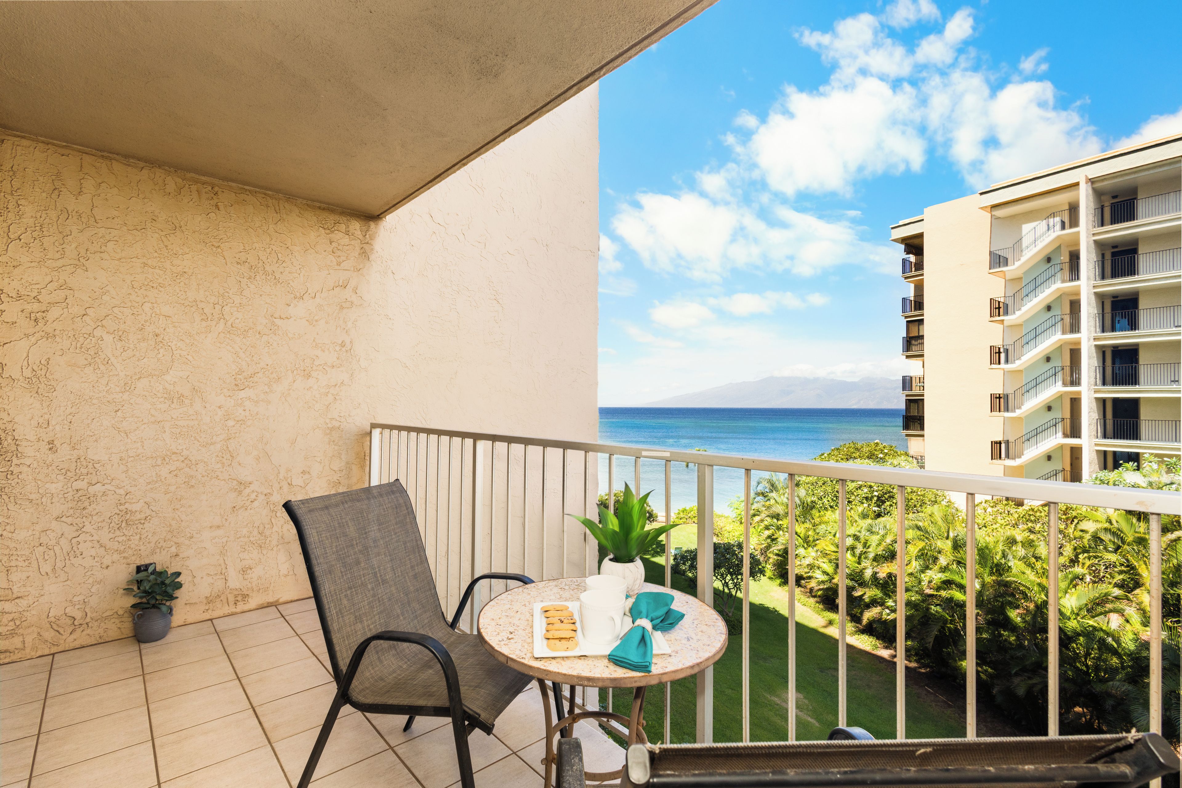 A balcony with a chair, a small table, and a potted plant.