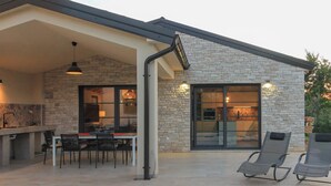 Uma casa moderna com fachada de pedra, uma piscina e área de jantar com assentos externos.
