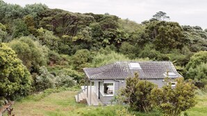 Una casita con techo inclinado, rodeada de abundante vegetación y árboles.