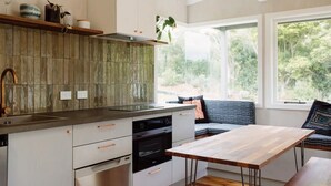 Una cocina moderna con encimera de madera, horno integrado y comedor con mesa y sillas de madera.