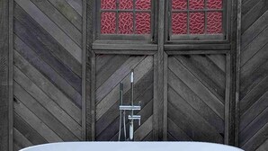 A freestanding bathtub in a wooden outdoor setting. - Wainui Stream Cottage (Raglan)