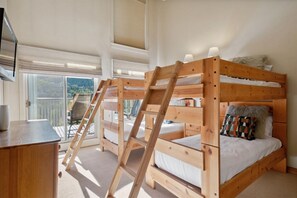 Een slaapkamer met een stapelbed, een bureau en uitzicht op de natuur.