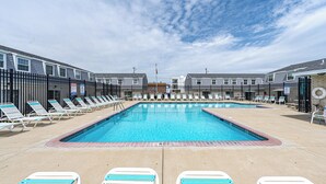 Une piscine avec des chaises longues et un bâtiment en arrière-plan.