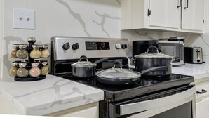 A kitchen with a stove, pots, a toaster, and a spice rack. - Spacious house with massage chair and game room (Beaumont)