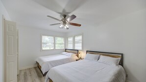 A bedroom with two beds, a ceiling fan, and a window with blinds. - Spacious house with massage chair and game room (Beaumont)