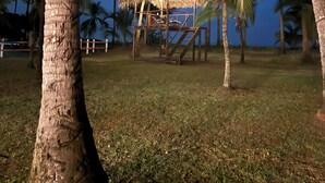 A thatched-roof structure with a staircase, surrounded by palm trees and grass. - Pacific Ocean-Front Villa de Azul. stunning Sunrises & Sunsets, 3bd 2 full baths (Provincia de Puntarenas)