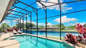 Area piscina con vista sul lago, lettini e zona coperta con tetto.