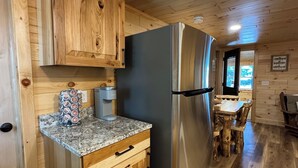 Una cocina con armarios de madera, un refrigerador de acero inoxidable, encimera de granito y un comedor con mesa y sillas de madera.