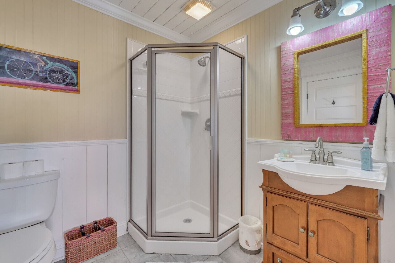 Een badkamer met douche, toilet en wastafel.