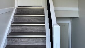 A staircase with a white door at the top, a handrail on the right, and a wall with a light color. - Upper level home in Grande Prairie (Grande Prairie)
