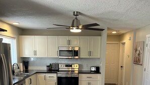 A modern kitchen with white cabinets, stainless steel appliances, and a black countertop. - Upper level home in Grande Prairie (Grande Prairie)