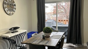 A modern dining area with a wooden table, black chairs, a potted plant, and a decorative clock on the wall. - Upper level home in Grande Prairie (Grande Prairie)