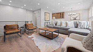 A modern living room with a sofa, armchairs, a coffee table, and a rug. - Platinum-rated 2 Bedroom ski in, ski out Condo in BC Village (Avon)