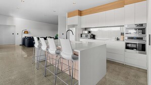 A modern kitchen with white cabinets, stainless steel appliances, and a central island with bar stools.