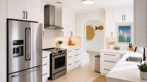 Une cuisine moderne dotée d’appareils électroménagers en acier inoxydable, de meubles blancs et d’un îlot central.