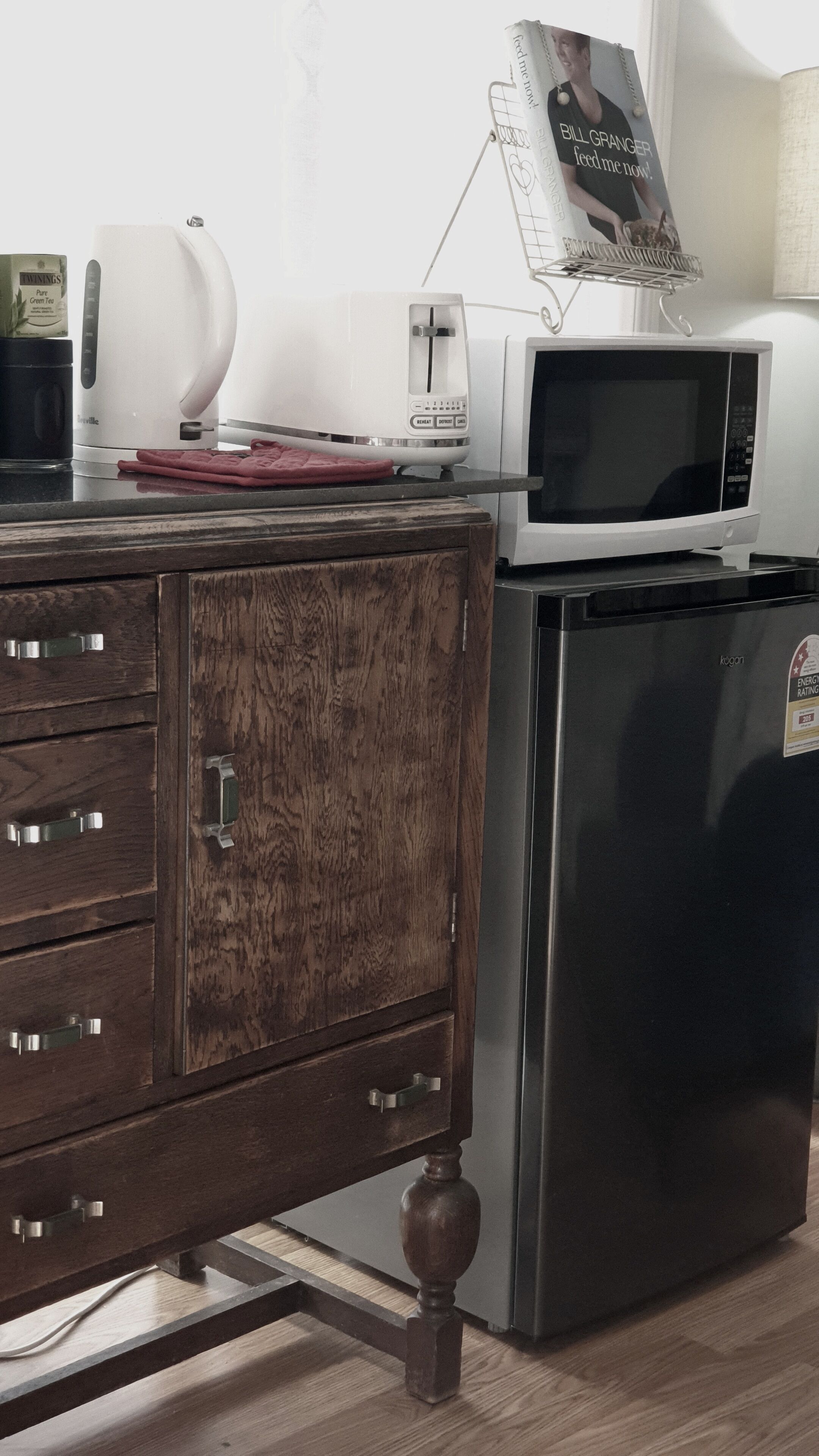 A kitchen with a stainless steel refrigerator, a microwave, a toaster, and a kettle.